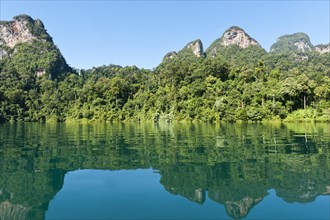 Forested karst limestone mountains with jungle vegetation reflected in the water