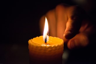 Finger next to a burning wax candle
