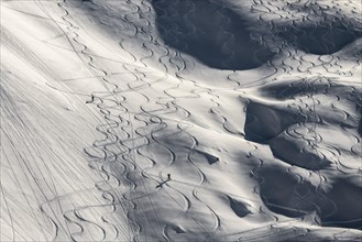 Ski tracks and tour hikers climbing between ski tracks on slopes with deep snow