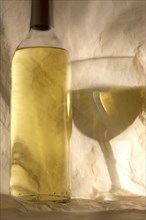 White wine bottle and the reflection of a wine glass on tissue paper