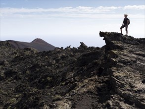 A hiker standing on a rock in the volcanic landscape
