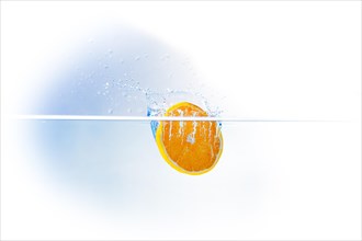 A slice of orange falling into water