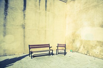 Chair and bench in front of house wall