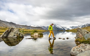 Hiker walks over stones in the water