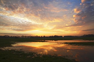 Dramatic sky at sunset with reflection in flooded meadow