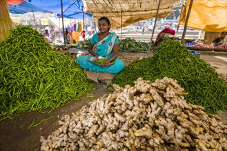 A woman is selling ginger and chilis at the weekly vegetable market