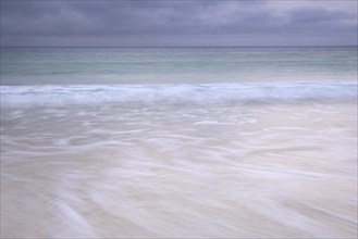 Spray and waves running on a sandy beach