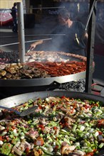 Large pan containing ingredients for the paella in front of a giant barbecue at the annual All Saints Market in Cocentaina