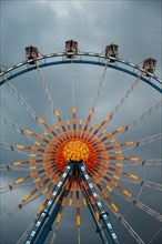 Ferris wheel against dark clouds