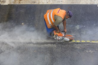 Road construction worker operating a disc cutter
