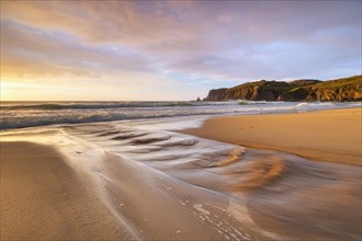 A brook flows over the sandy beach into the sea