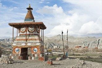 Colourfully decorated Buddhist stupa at the entrance to the village