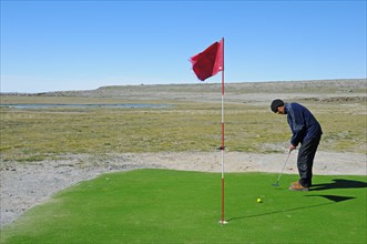 Man hitting a golf ball on the northernmost golf course in the world