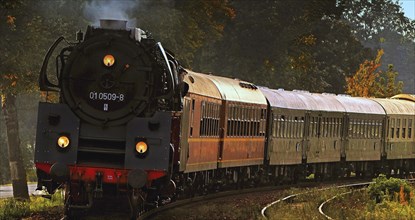 Train with old carriages of the Deutsche Reichsbahn railway being pulled by a steam locomotive