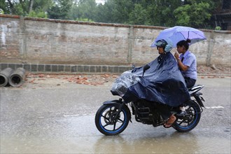 People on motorcycle on flooded road after monsoon storm