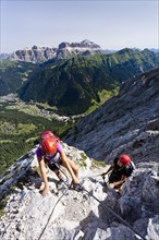Mountain climbers ascending along the Via ferrata dei Finanzieri climbing route to the summit of Colac Mountain in the Fassa Valley