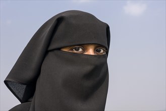 A portrait of a Muslim woman dressed in the traditional black chador