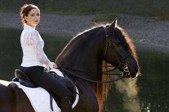 Horsewoman riding a black Friesian horse
