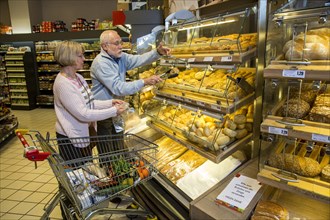 Senior couple shopping at a self-service bakery shop in the supermarket