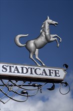 Hanging sign of 'Stadtcafe' against a blue sky