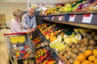 Senior couple shopping with a shopping trolley in the fruit and vegetables department of a supermarket