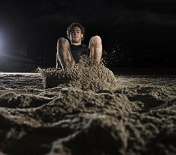 Athlete lands in the sand at the long jump