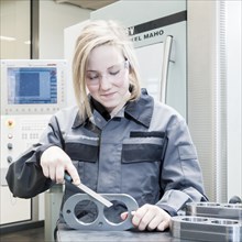 A female cutting machine operator trainee is deburring a component
