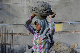 Female construction worker carrying concrete on her head