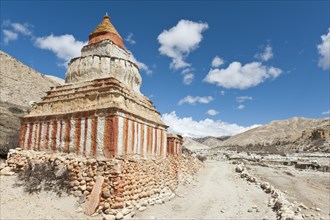 Colourfully decorated Buddhist stupa on a track in a vast landscape