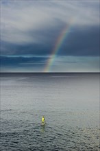 Standing paddler and a rainbow