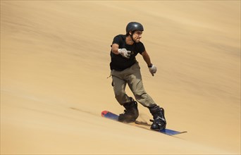 Sand boarding in the dunes of the Namib Desert