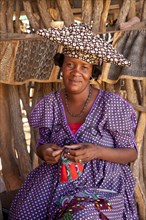 Herero woman with typical headdress sewing souvenirs