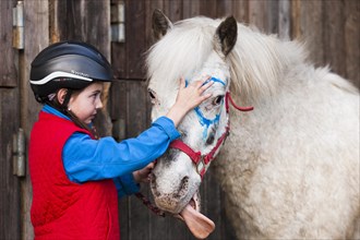 Girl wearing a riding helmet painting a pony with finger paints