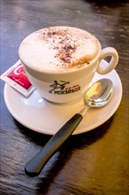 Cappuccino with a sugar sachet and a spoon
