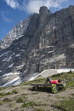 A hiker lying on a bench on the Eiger Trail