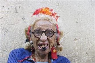 Old woman wearing coulorful clothes posing with a cigar