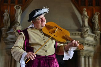Musician in period costume performing on a medieval fiddle