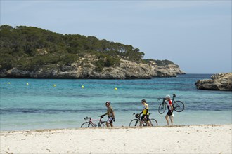 Racing cyclists walking along the beach