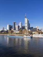 Cargo ship on the Main river in front of the skyline of Frankfurt with the buildings of Opernturm