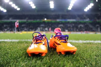 Orange-coloured Adidas football boots on the edge of the pitch