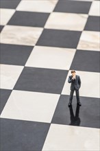 Figurine of a businessman standing on a chessboard