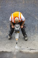 Road construction worker operating a pneumatic drill