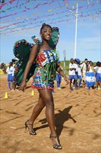 Teenage girl presenting a butterfly costume made of recycled materials such as lids of plastic bottles at a fashion show of a social project