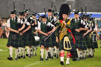 Pipe major leading a pipe band on the sports ground at the Highland Games
