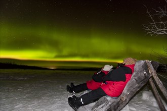 Two people sitting in a wooden chair