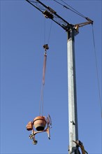 Concrete mixer hanging from a crane