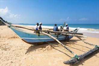 Traditional fishermen with an outrigger boat on the beach