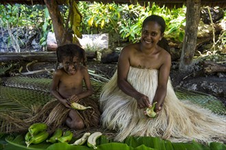 Woman with her little daughter preparing traditional food with bananas