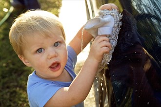 Young boy helping to wash a car