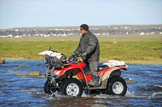 Man of the Inuit people riding a quad bike